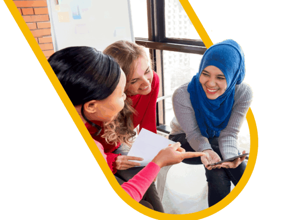 An ethnically diverse trio of women sitting together, laughing